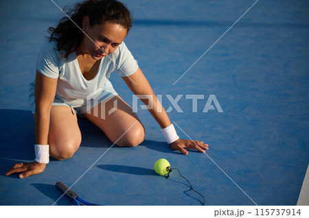 Woman enjoying a sunny day playing tennis on court 115737914
