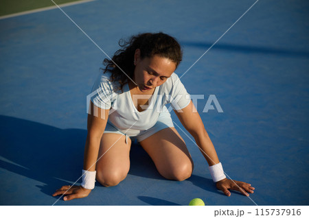 Tired female tennis player resting on court after match 115737916