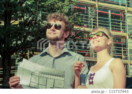 Couple on front of new house with blueprint project Couple on front of new house with blueprint project 115737943