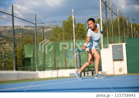 Young woman playing tennis on a sunny outdoor court 115738043