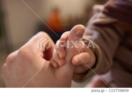 A close up of a persons thumb touching a baby tiny finger 115739609