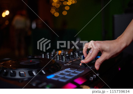 control DJ for mixing music with blurred people dancing at party in nightclub. 115739634