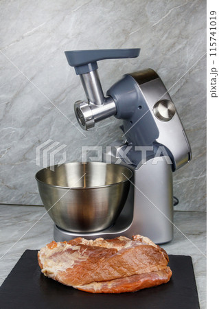 Electric eat grinder and fresh meat on kitchen table. Preparation of minced meat 115741019