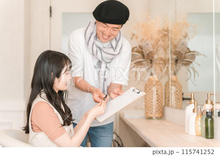 美容室・ヘアサロンで働く男性美容師と顧客の女性（カウンセリング・ヒアリング・髪型） 115741252