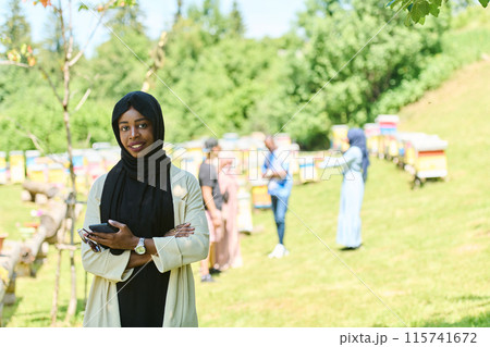 Empowered Middle Eastern Muslim Woman in Hijab Balances Modern Technology and Traditional Beekeeping Business 115741672