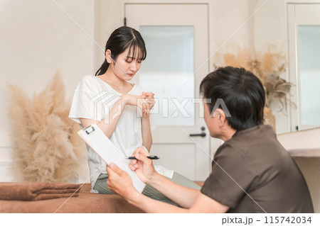 指の怪我で整体院・整骨院・マッサージに通う女性と整体師・セラピスト 指の怪我で整体院・整骨院・マッサージに通う女性と整体師・セラピスト 115742034