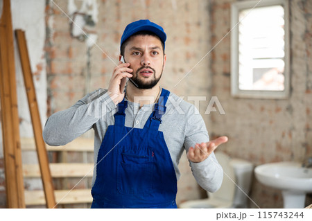 Builder talking on phone at construction site 115743244