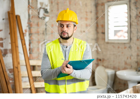 Qualified builder writes notes on a tablet Qualified builder writes notes on a tablet 115743420