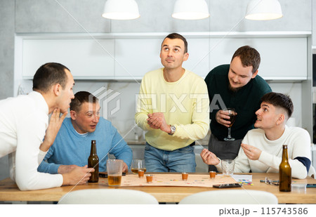 Group of friends excitedly playing board games and drinking beer at home 115743586