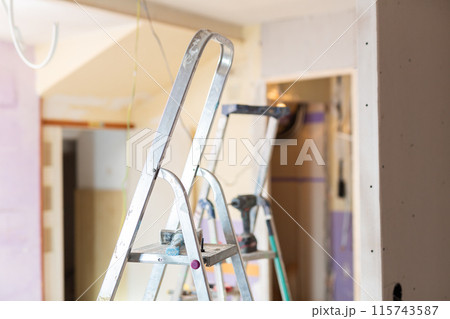 Interior of room being repaired with stepladder and wires 115743587