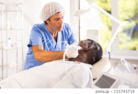 Specialist administers cosmetic treatment Specialist administers cosmetic treatment 115743719