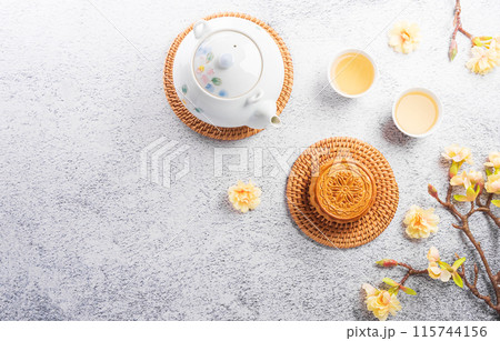 Chinese Mid-Autumn Festival concept made from mooncakes, tea and plum blossom on stone background. Chinese Mid-Autumn Festival concept made from mooncakes, tea and plum blossom on stone background. 115744156