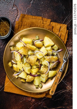 Warm Potato salad with red onion, capers, greens in a plate. Dark background. Top view Warm Potato salad with red onion, capers, greens in a plate. Dark background. Top view 115745076