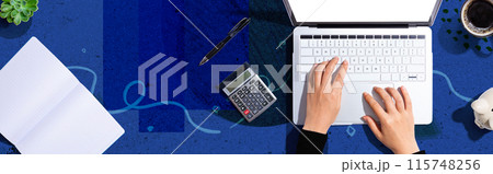 Woman using a laptop computer with a calculator 115748256