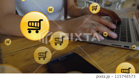 Image of shopping cart icon in circles, midsection of caucasian woman working on laptop 115748573