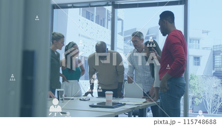 Image of flowcharts of profile icons over diverse coworkers discussing floor plan on blueprint 115748688