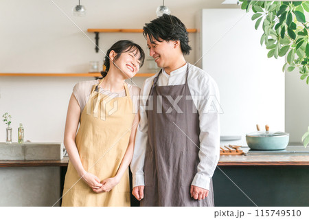 マイホームのキッチン・ダイニングで笑うエプロン姿の夫婦・カップル・恋人・パートナー 115749510