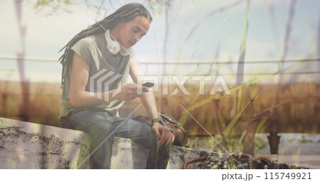 Image of grass over biracial man using smartphone 115749921