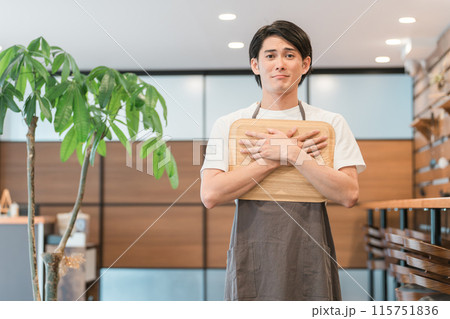 カスハラを受けて困る・悲しい表情のカフェの店員・ホール係の若いアジア人男性 カスハラを受けて困る・悲しい表情のカフェの店員・ホール係の若いアジア人男性 115751836