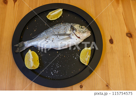 Raw fresh fish dorado with lemon and spices on wooden table. Top view Raw fresh fish dorado with lemon and spices on wooden table. Top view 115754575