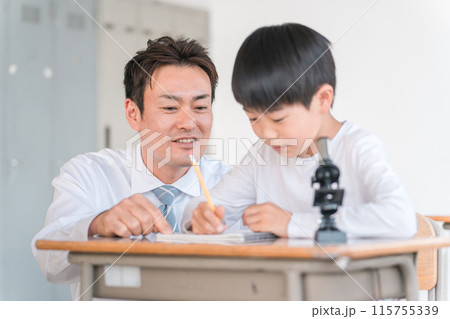 学校の授業で理科の実験・観察・研究・勉強をする小学生の男の子と先生・教師(顕微鏡) 115755339