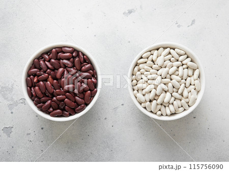 Ceramic bowls with white and red raw dry beans on kitchen table. 115756090