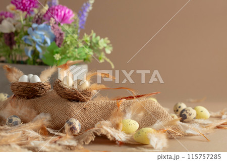 Easter composition with eggs, feathers, and spring flowers on a beige background. Easter composition with eggs, feathers, and spring flowers on a beige background. 115757285