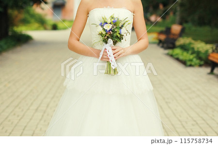 Beautiful lovely bride in white wedding dress holding bouquet of flowers 115758734