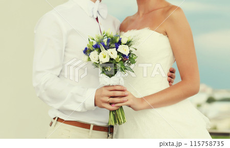 Wedding couple, bride in white dress with bouquet of flowers and groom in shirt holding hands 115758735