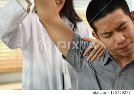 Physical therapist helping male patient doing stretching exercises, shoulder joint treatment Physical therapist helping male patient doing stretching exercises, shoulder joint treatment 115759277