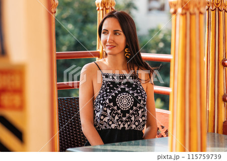 A beautiful woman in an oriental dress is sitting at a table. The concept of luxury living A beautiful woman in an oriental dress is sitting at a table. The concept of luxury living 115759739