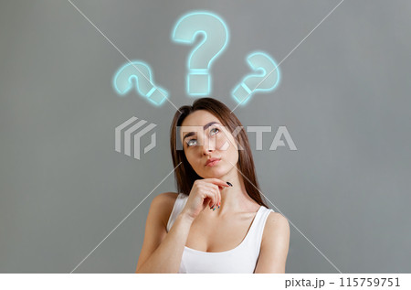 The concept of searching for ideas and information. Portrait of thoughtfully young Caucasian woman looking up at question marks. Gray background. Copy space 115759751
