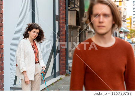 Young Caucasian woman smiling and looks at blurred handsome young man passing by on street. Psychology of relationship 115759758