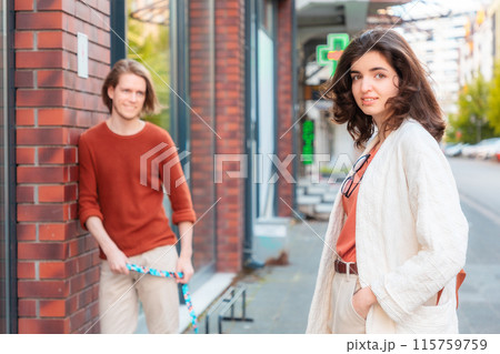 Blurred young Caucasian Man smiling and looks at beautiful young woman passing by on street and looks at camera. Psychology of relationship 115759759