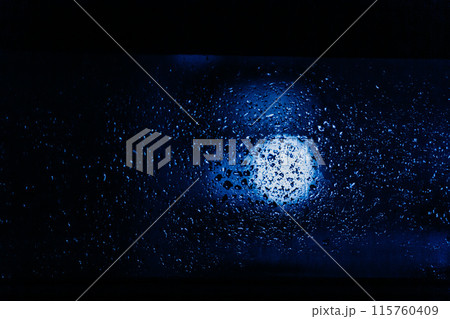Raindrops and condensation on window at night with street lights. Cinematic dramatic background 115760409