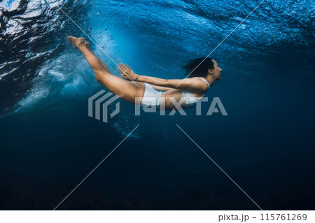 Surfer girl dive under powerful wave in ocean. 115761269