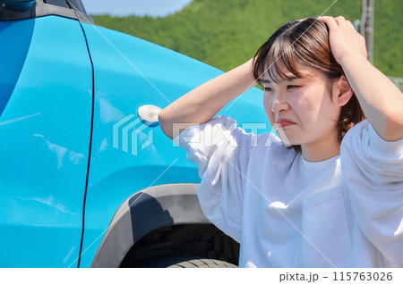 車の前で頭を抱える女性 パンク トラブル 車の前で頭を抱える女性 パンク トラブル 115763026