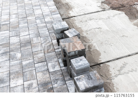 Street paving works in progress. Gray paving slabs lay on the ground 115763155