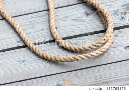 Nautical rope lies on weathered wooden floor Nautical rope lies on weathered wooden floor 115763176