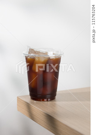 Iced americano in clear cup on wooden table. 115763204