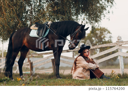 Cowgirl in brown clothes with her horse at outdoors ranch 115764200