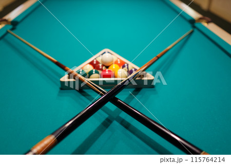 Billiard accessories balls and crossed cues on a billiard table Billiard accessories balls and crossed cues on a billiard table 115764214
