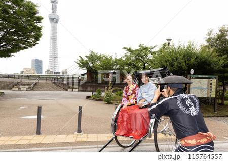 スカイツリーを背景に人力車に乗る着物姿の外国人女性と日本人女性 115764557