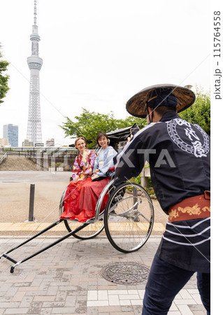 スカイツリーを背景に人力車に乗る着物姿の外国人女性と日本人女性 115764558