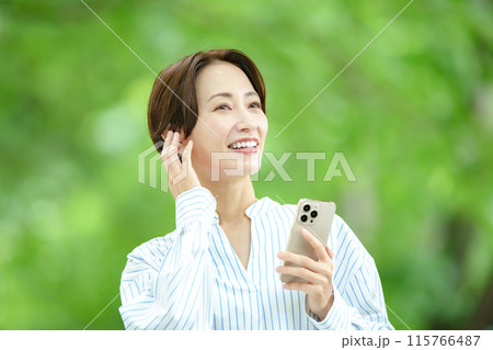 新緑の中で音楽を聴く女性 115766487