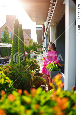 Beautiful young pregnant woman in pink dress on summer veranda. Beautiful young pregnant woman in pink dress on summer veranda. 115767376