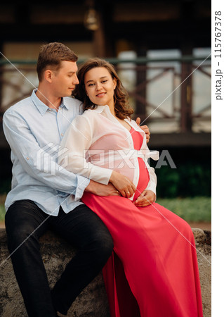 Man gently hugging pregnant woman while sitting in garden at home. Man gently hugging pregnant woman while sitting in garden at home. 115767378