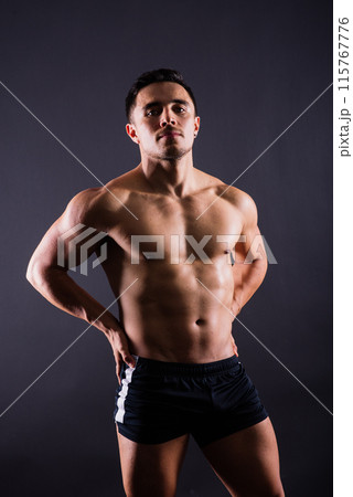 Muscular shirtless young man standing confident, front view, looking at camera 115767776