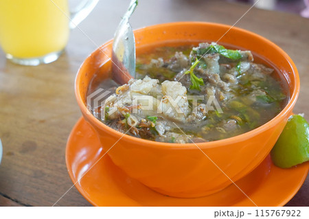 A bowl filled with rib soup on a light wooden table. A bowl filled with rib soup on a light wooden table. 115767922