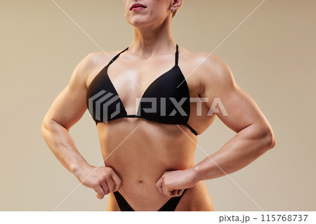 Cropped close up on unrecognizable female bodybuilder posing in black bikini performing front lat spread isolated in studio against neutral background, copy space 115768737